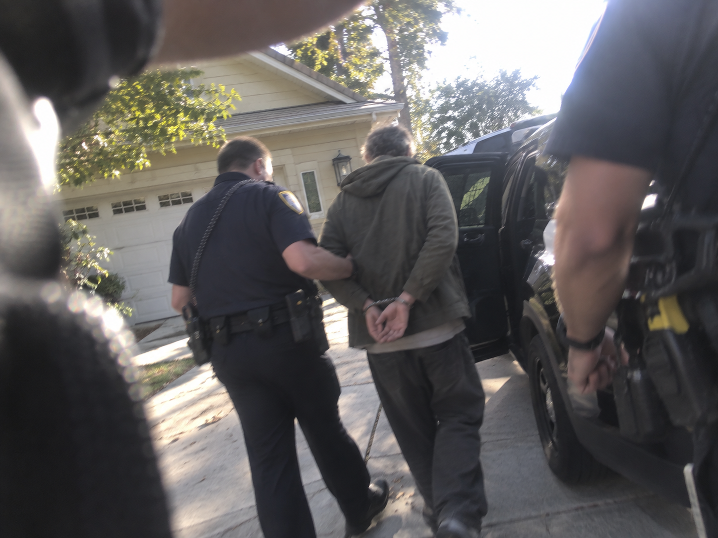 Illustrative dramatization of a man being arrested outside a home.